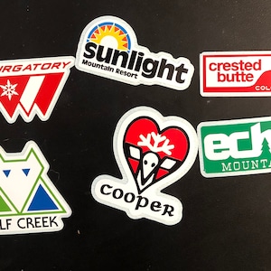 May include: A collection of nine colorful ski resort stickers. The stickers feature the names of the resorts, including Purgatory, Sunlight Mountain Resort, Crested Butte, Colorado, Echo Mountain, Wolf Creek, and Cooper. The stickers are all different shapes and sizes, and they are all printed on white paper.