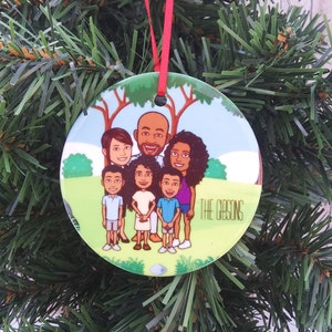 Könnte beinhalten: Ein runder Weihnachtsbaumschmuck mit einer fünfköpfigen Zeichentrickfamilie. Die Familie steht vor einem grünen Baum und der Text "THE GIBSONS" ist auf dem Schmuckstück gedruckt.