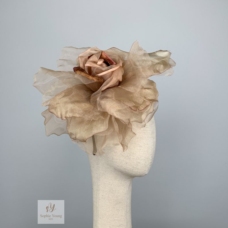 K&ouml;nnte beinhalten: Eine gro&szlig;e, beige Stoffrose mit einer kleineren, dunkleren Rose in der Mitte. Die Rose befindet sich auf einem Mannequin-Kopf.