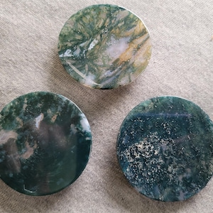 May include: Three round agate coasters with green, brown and white patterns. The coasters are made of natural stone and have a polished finish.