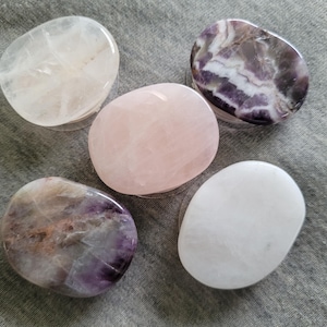 Könnte beinhalten: Fünf glatte, polierte, ovalförmige Steine. Zwei sind weiß, einer ist rosa und zwei sind lila und weiß mit Wirbeln.
