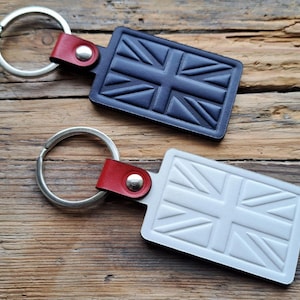 Puede incluir: Dos llaveros de cuero con un diseño de Union Jack. Un llavero es negro y el otro es blanco.