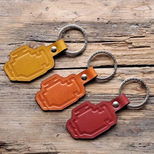May include: Three leather keychains with engine check light symbols. The keychains are yellow, orange, and red.