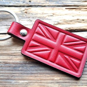 Puede incluir: Llavero de cuero rojo con un dise&ntilde;o de Union Jack. El llavero tiene un anillo de metal plateado.