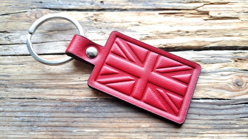 Puede incluir: Llavero de cuero rojo con un dise&ntilde;o de Union Jack. El llavero tiene un anillo de metal plateado.
