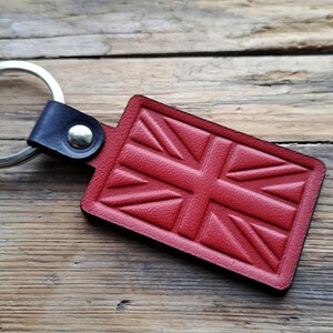 Puede incluir: Llavero de cuero rojo con un dise&ntilde;o de Union Jack. El llavero tiene un anillo plateado y una correa de cuero negro.