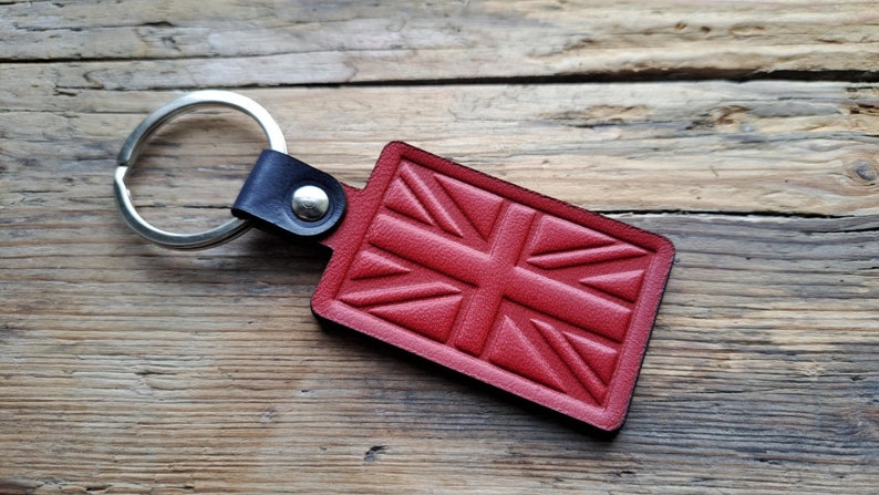 Puede incluir: Llavero de cuero rojo con un dise&ntilde;o de Union Jack. El llavero tiene un anillo plateado y una correa de cuero negro.