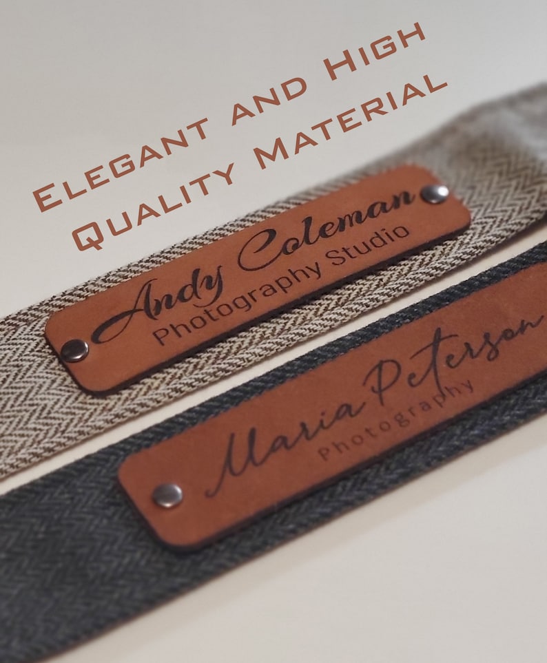 May include: Two brown leather camera straps with engraved text. The top strap says "Andy Coleman Photography Studio" and the bottom strap says "Maria Peterson Photography". The straps are made of high quality material.