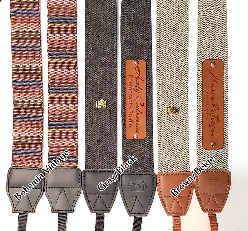 May include: Four camera straps with different patterns and colors. The straps are made of woven fabric and have leather ends. The straps have personalized leather tags with the names "Andy Coleman Photography Studio" and "Maria Peterson Photography".