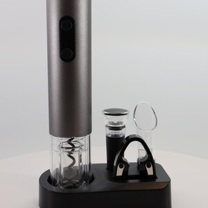 May include: A grey electric wine opener with a black base and a clear plastic housing for the corkscrew. The opener comes with a foil cutter, a bottle stopper, and a pourer.