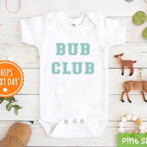 May include: White baby onesie with the text "Bub Club" in teal blue lettering.