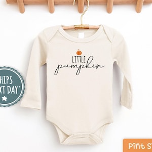 May include: A cream-colored long-sleeved bodysuit with the text "Little pumpkin" and a small orange pumpkin graphic.