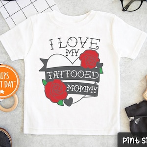 May include: White baby onesie with a red heart graphic and the text "I love my tattooed mommy".