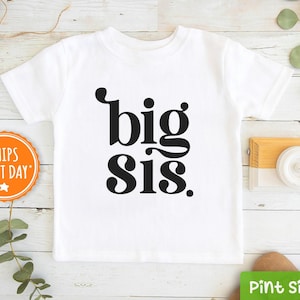 May include: White t-shirt with black text that says "big sis" in a retro font.