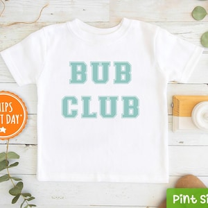 May include: White t-shirt with the text "BUB CLUB" in teal blue lettering.