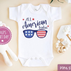 May include: White baby onesie with the text "All American babe" and a pair of sunglasses with red, white, and blue stripes.