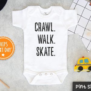 May include: White baby bodysuit with black text that reads "Crawl. Walk. Skate."  The bodysuit has a snap closure at the crotch.