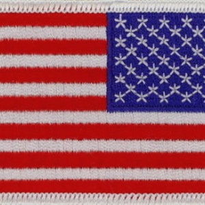 May include: Embroidered patch featuring the American flag. The design includes red and white stripes and a blue canton filled with white stars. The patch has a white border and is likely for application on clothing or accessories.