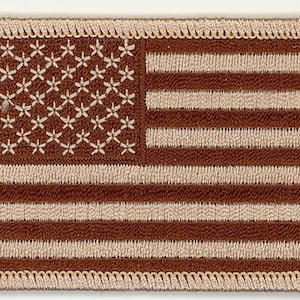 May include: Embroidered patch featuring the American flag in shades of brown and beige. The flag's stars are represented by white floral patterns on a brown background. The stripes alternate between brown and beige. The patch has a beige border.