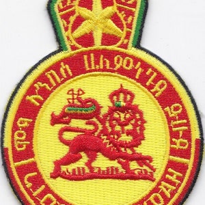 Puede incluir: Parche bordado con un león amarillo con corona, rodeado de texto rojo que dice "Lion of Judah". El parche tiene un diseño de corona roja y verde en la parte superior. El parche es de forma circular.