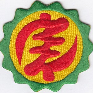 May include: A red embroidered Chinese character on a yellow background surrounded by a green scalloped border.