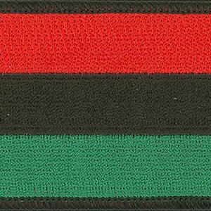May include: A red, black, and green fabric patch with a woven texture. The patch is rectangular and has a black border.
