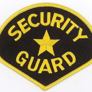 May include: A black and yellow security guard patch. The patch has a black background with the words "SECURITY GUARD" in yellow block letters. A yellow star is in the center. The patch is outlined in yellow.