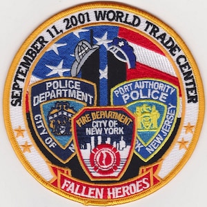 May include: A circular patch commemorating the September 11, 2001 World Trade Center attacks. The design features the American flag, the Twin Towers, and emblems for the Police and Fire Departments. Text includes "Fallen Heroes".