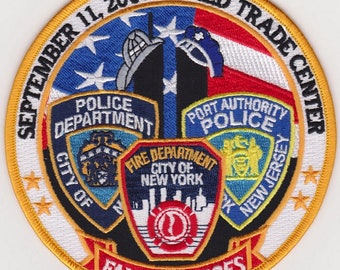 May include: A circular patch commemorating the September 11, 2001 World Trade Center attacks. The design features the American flag, the Twin Towers, and emblems for the Police and Fire Departments. Text includes "Fallen Heroes".