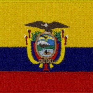 May include: A yellow, blue, and red embroidered patch featuring the coat of arms of Ecuador. The coat of arms is a shield with a condor, a mountain, and a river. The shield is surrounded by a wreath of laurel leaves and a ribbon with the words "República del Ecuador".