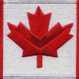 May include: A rectangular embroidered patch featuring the Canadian flag design. The patch displays two solid red vertical bands on the left and right sides, with a white central square containing a prominent, detailed red maple leaf emblem.