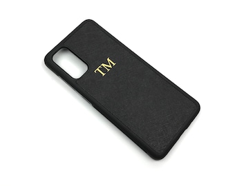 May include: Black phone case with a textured surface and gold lettering that says "TM".
