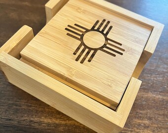 Peut inclure: Un ensemble de quatre dessous de verre carrés en bambou avec un support assorti. Chaque dessous de verre présente un symbole du soleil Zia gravé au laser, un motif amérindien. Les dessous de verre et le support sont en bambou de couleur claire.