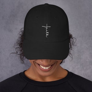 May include: Black baseball cap with a white embroidered cross and the word "faith" on the front.