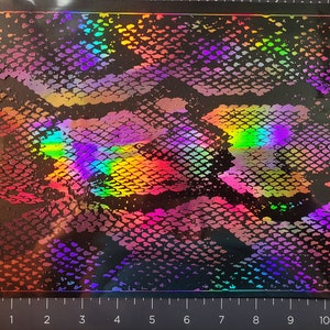 May include: A sheet of iridescent holographic vinyl with a snakeskin pattern. The vinyl is black with a rainbow sheen.