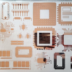 May include: A sheet of gold-colored adhesive vinyl with various shapes and designs of computer chips, circuit boards, and other electronic components. The designs are cut out of the vinyl, leaving a gold outline.