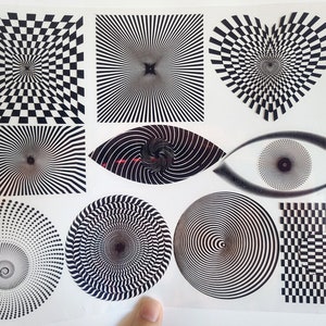 May include: A sheet of black and white optical illusion stickers. The stickers feature various designs, including a checkered pattern, a spiral, an eye, and a heart.