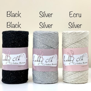 May include: Three spools of cotton macrame cord in black, silver, and ecru. The spools are labeled "Hobby Club Cotton Macrame made for you."