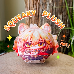 May include: A plush toy with a character design, featuring orange and red hair, and a detailed outfit. The text "SQUEAKY PLUSH" is written above the toy. The toy is placed on a wooden surface.