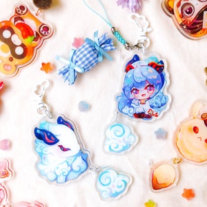 May include: A set of four acrylic charms featuring a blue and white gingham candy, a blue-haired character with a white coat and blue wings, a white character with blue wings, and a blue and white cloud. The charms are attached to silver chains.