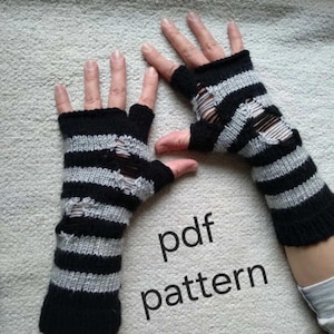 May include: A pair of fingerless gloves featuring a horizontal striped pattern in black and light gray. The knit fabric includes intentional distressed holes throughout the design. The text "pdf pattern" is printed in black on the lower right side.