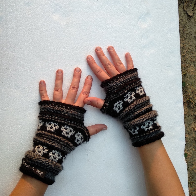 May include: A pair of brown and white fingerless gloves with a geometric pattern. The gloves have a tag that says "Your Name".