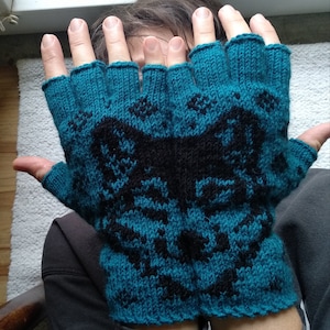 May include: A pair of teal blue fingerless gloves with a black and white geometric pattern. The gloves are knitted and have a textured surface.