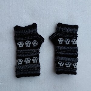 May include: A pair of black and gray fingerless gloves with a white snowflake pattern.