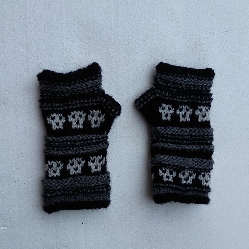 May include: A pair of black and gray fingerless gloves with a white snowflake pattern.