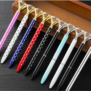 May include: A set of ten pens with diamond-shaped tops. The pens have polka dot patterns in various colors, including pink, white, blue, red, and black.