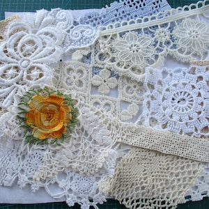 May include: Assortment of white and cream lace doilies and trim pieces, including a small yellow floral embellishment.