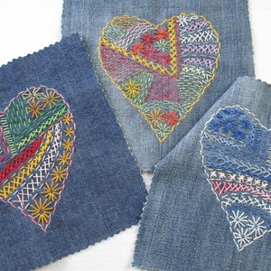 Puede incluir: Tres cuadrados de mezclilla con corazones bordados en diferentes colores. Los corazones están hechos con varios puntos y colores, incluyendo rojo, azul, verde, amarillo y rosa.
