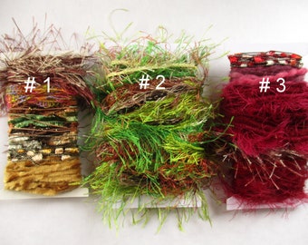 May include: Three spools of colourful fuzzy yarn, labelled #1, #2, and #3. The yarn is a mix of brown, green, red, and gold.