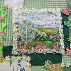 Può includere: Una trapunta patchwork verde e bianca con una varietà di trame e colori di tessuto. La trapunta presenta un pannello centrale con una foglia verde e un bordo in pizzo bianco. La trapunta è decorata con fiori rosa e verdi e una farfalla blu.